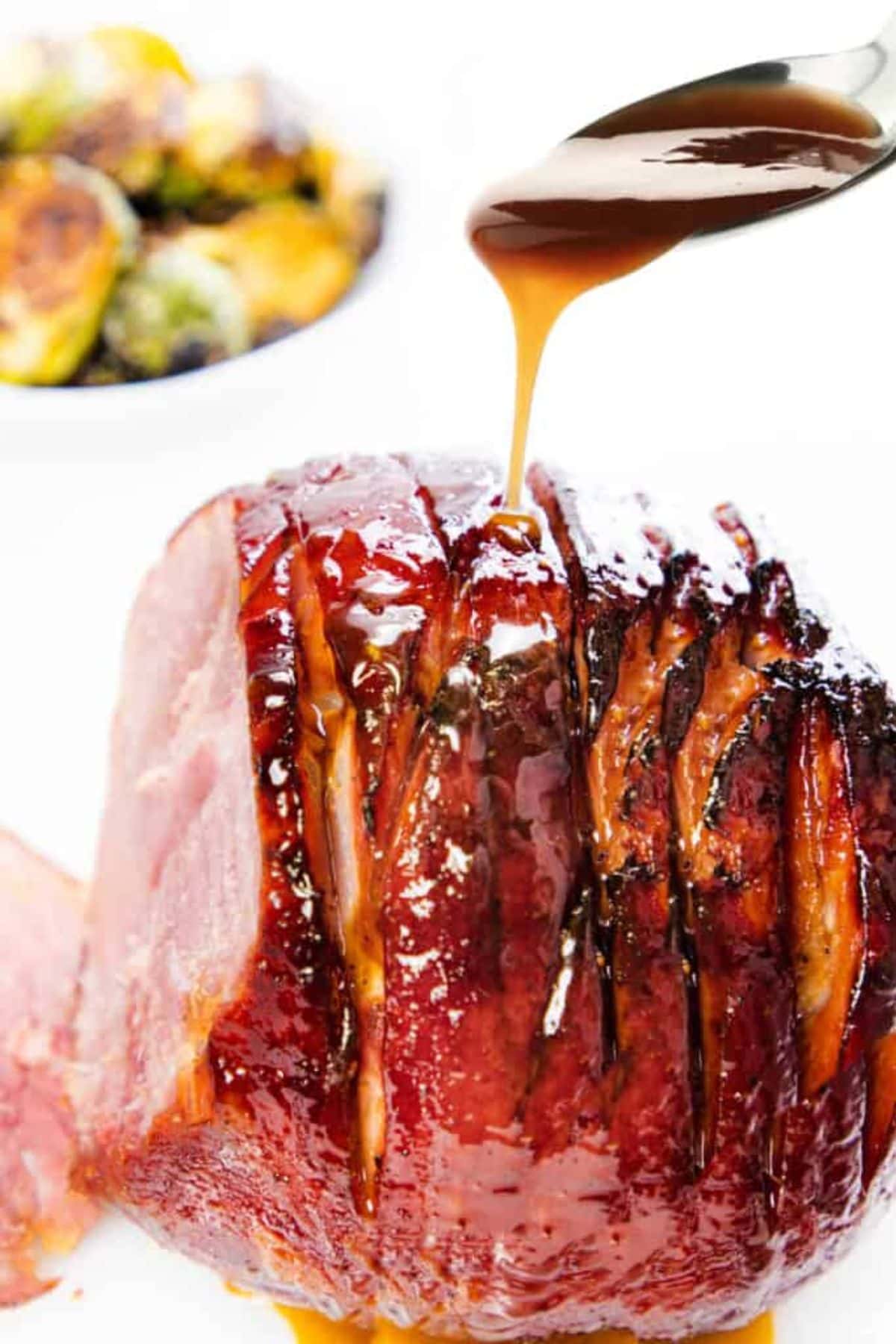 Honey glaze being poured on ham. 