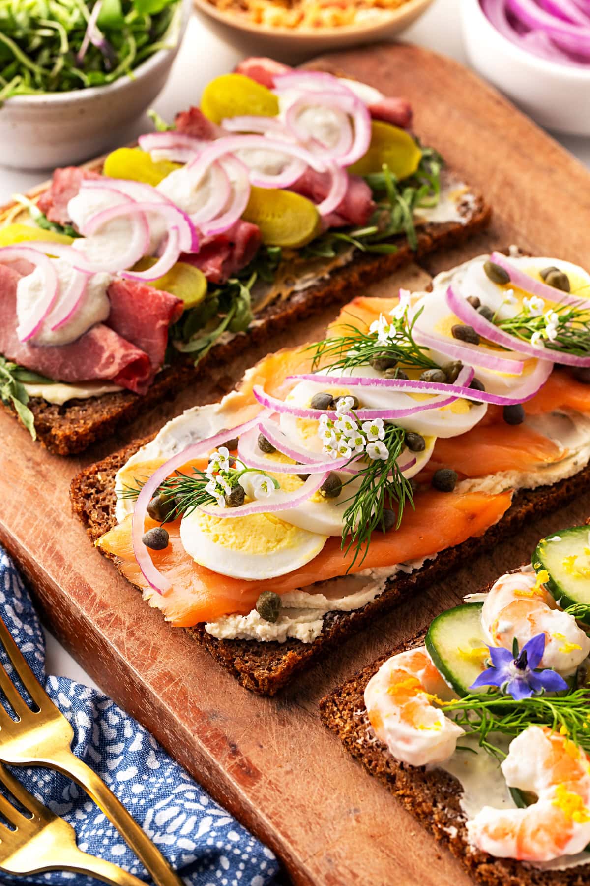 Three Sm&oslash;rrebr&oslash;d sandwiches on a board. 